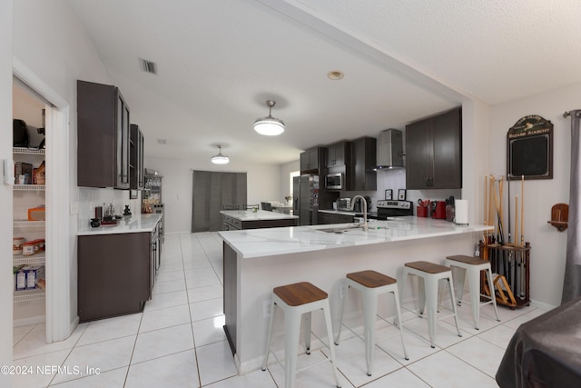 kitchen with visible vents, a peninsula, light tile patterned flooring, a sink, and appliances with stainless steel finishes