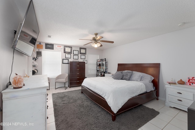 bedroom with light tile patterned floors, a ceiling fan, visible vents, and a textured ceiling