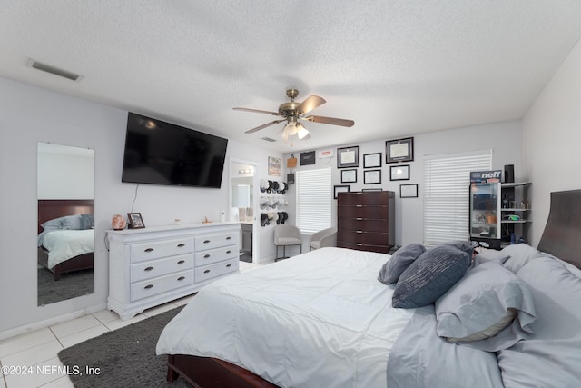 bedroom with light tile patterned flooring, visible vents, a textured ceiling, and ceiling fan