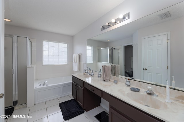 full bathroom featuring a garden tub, double vanity, a stall shower, tile patterned floors, and a sink