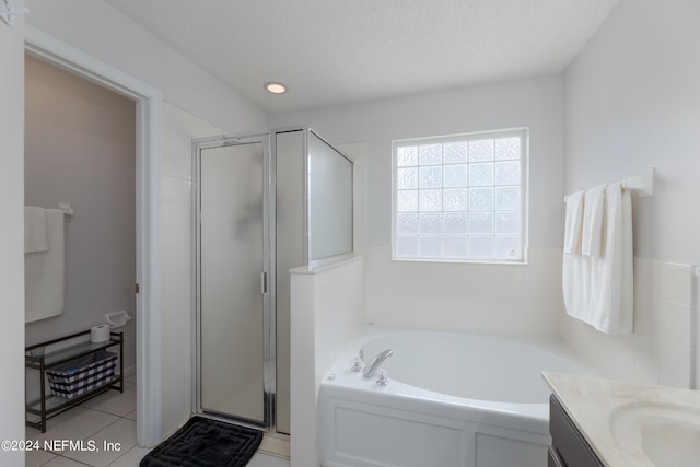 full bath featuring a stall shower, a textured ceiling, tile patterned flooring, a bath, and vanity