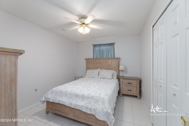 bedroom featuring baseboards, ceiling fan, light tile patterned flooring, a closet, and a textured ceiling