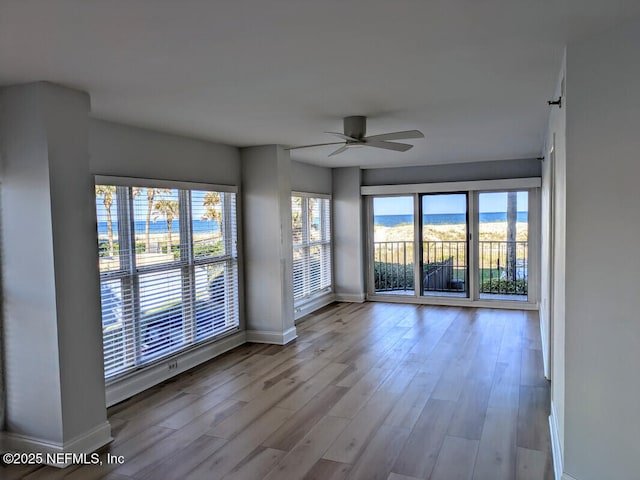 empty room with a ceiling fan, wood finished floors, and baseboards