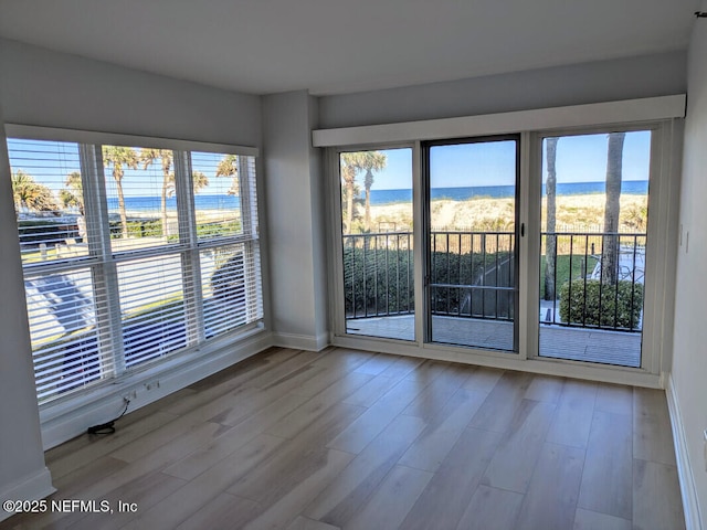 spare room with a water view, baseboards, and wood finished floors