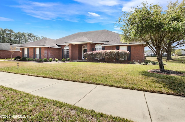 view of front of house with a front yard, fence, and brick siding