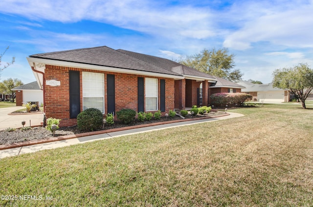 view of side of property featuring brick siding, a shingled roof, and a yard