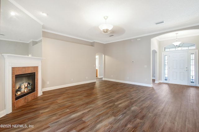 unfurnished living room with visible vents, baseboards, arched walkways, and dark wood-style flooring