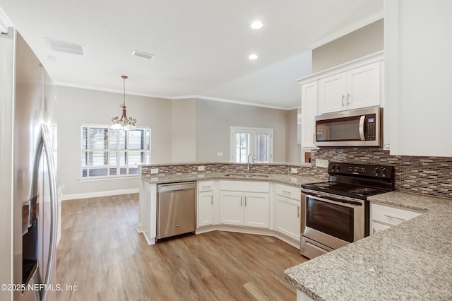 kitchen with visible vents, backsplash, appliances with stainless steel finishes, a peninsula, and a sink