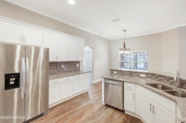 kitchen featuring light wood-type flooring, a notable chandelier, a sink, stainless steel appliances, and arched walkways