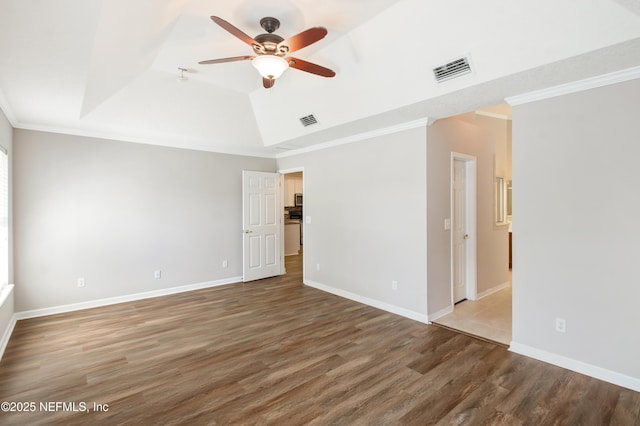 empty room with crown molding, wood finished floors, and visible vents