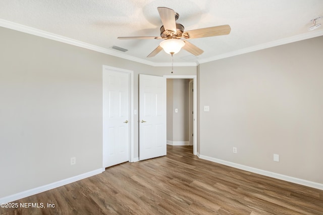 empty room featuring crown molding, baseboards, wood finished floors, a textured ceiling, and a ceiling fan