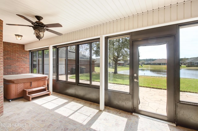 unfurnished sunroom with a healthy amount of sunlight, ceiling fan, and a water view