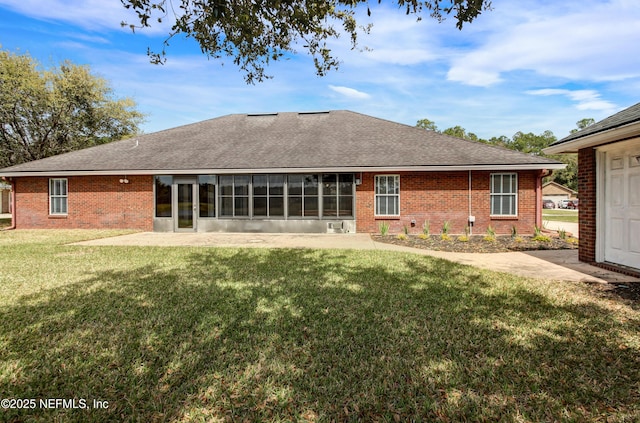 back of house with brick siding, a lawn, and roof with shingles