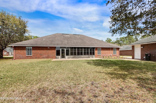 rear view of house with a lawn, roof with shingles, brick siding, and a sunroom