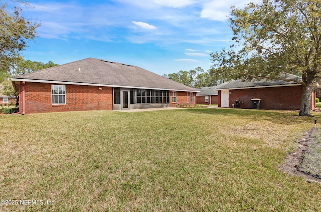 back of property with brick siding, a lawn, roof with shingles, and a sunroom