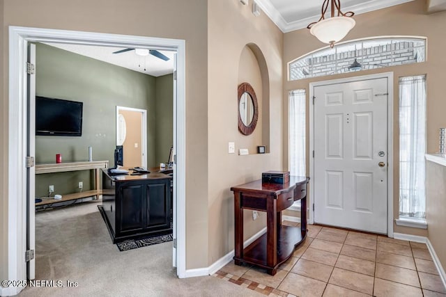 entryway featuring baseboards, ornamental molding, light tile patterned floors, light carpet, and a ceiling fan