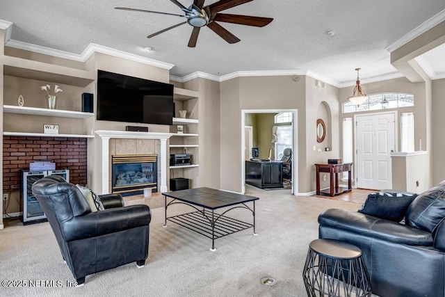 living area featuring crown molding, ceiling fan, light carpet, a fireplace, and a textured ceiling