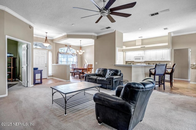 living room featuring visible vents, light carpet, ornamental molding, and ceiling fan with notable chandelier