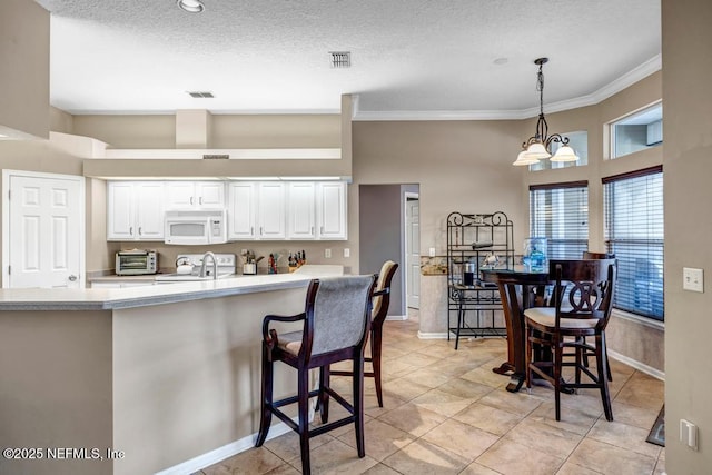 kitchen with visible vents, ornamental molding, white appliances, white cabinets, and light countertops