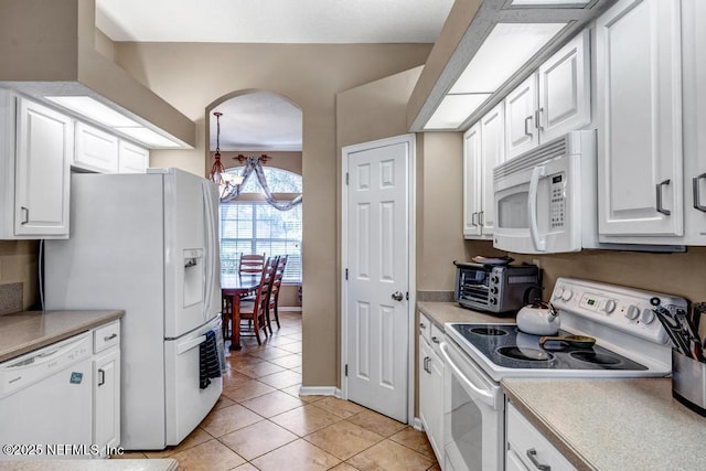 kitchen featuring white appliances, a toaster, light tile patterned flooring, arched walkways, and light countertops