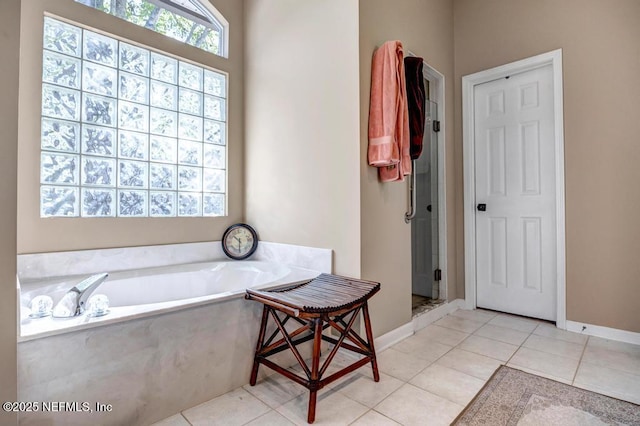 bathroom with tile patterned floors, a bath, baseboards, and a stall shower