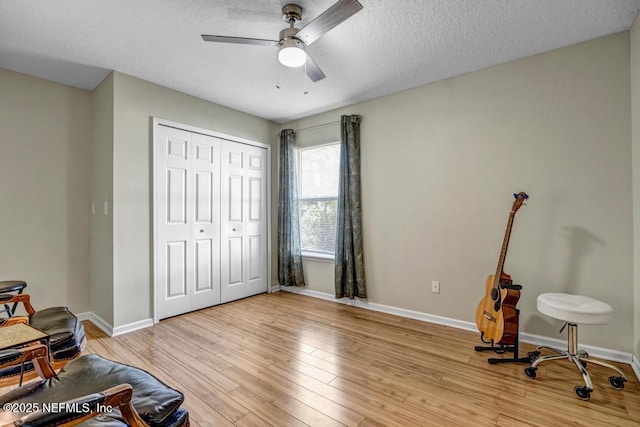 interior space with baseboards, a textured ceiling, light wood-style flooring, and a ceiling fan