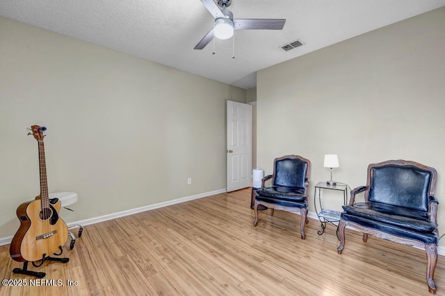 sitting room featuring light wood finished floors, visible vents, a ceiling fan, and baseboards