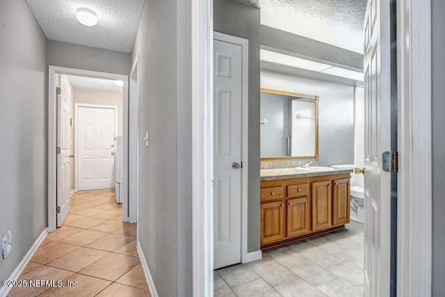 bathroom with tile patterned flooring, a textured ceiling, vanity, and baseboards