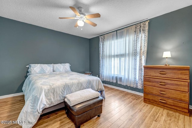 bedroom with a textured ceiling, a ceiling fan, baseboards, and wood finished floors