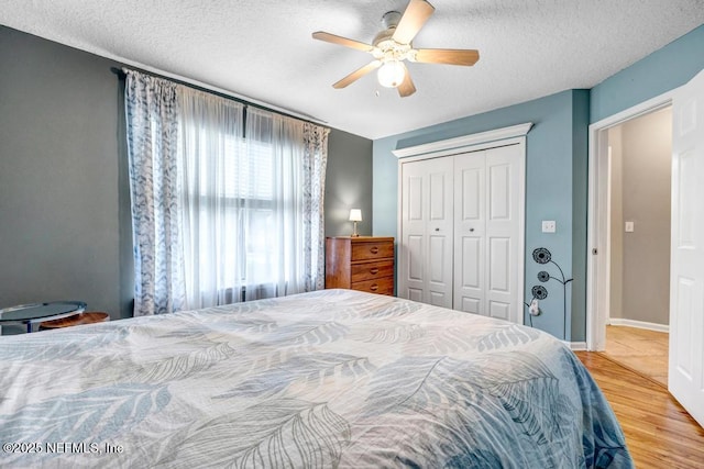 bedroom featuring a ceiling fan, wood finished floors, a closet, and a textured ceiling