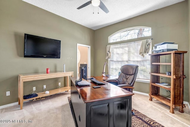 office area with a textured ceiling, light colored carpet, baseboards, and ceiling fan