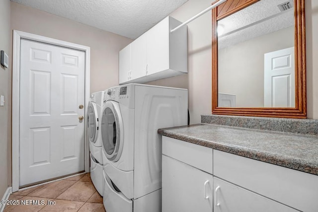 clothes washing area with visible vents, light tile patterned flooring, cabinet space, a textured ceiling, and independent washer and dryer