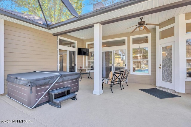 exterior space featuring glass enclosure and a hot tub