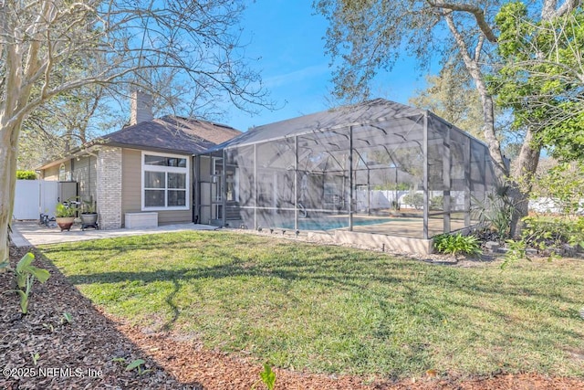 rear view of property featuring an outdoor pool, a chimney, a lanai, a patio area, and a lawn