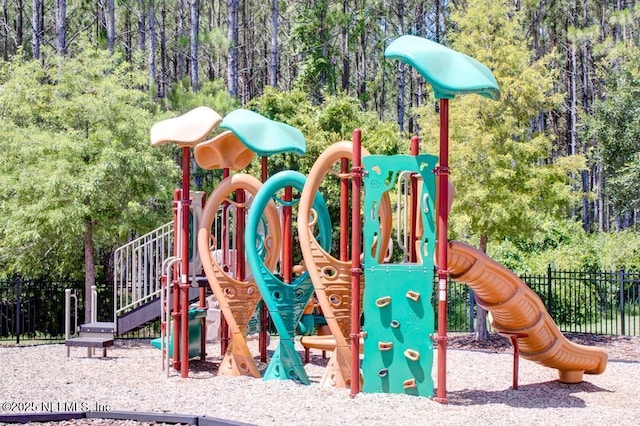 community playground featuring a view of trees and fence