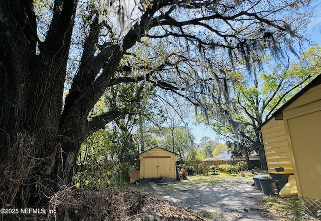 view of yard featuring a storage unit, an outdoor structure, and fence