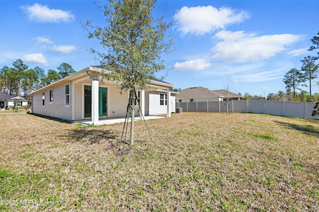 rear view of property featuring a patio area, a lawn, and fence