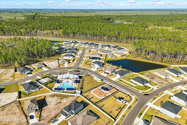 drone / aerial view with a residential view, a forest view, and a water view