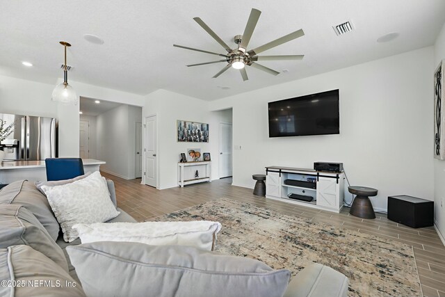 living area with visible vents, wood finish floors, baseboards, ceiling fan, and recessed lighting