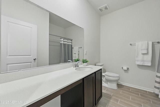 bathroom featuring visible vents, baseboards, wood tiled floor, toilet, and vanity