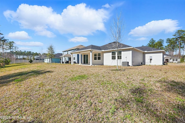 back of property with a yard and central AC