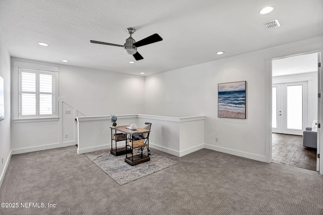 interior space with an upstairs landing, visible vents, ceiling fan, and carpet floors