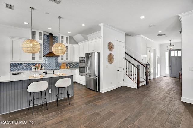 kitchen with visible vents, light countertops, wall chimney exhaust hood, and stainless steel refrigerator with ice dispenser