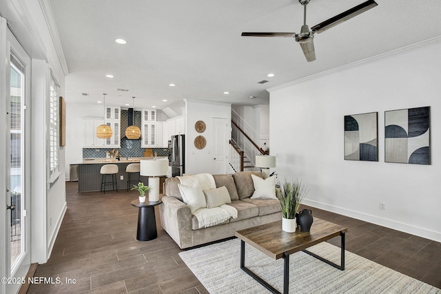 living room featuring a ceiling fan, recessed lighting, stairs, dark wood-type flooring, and crown molding