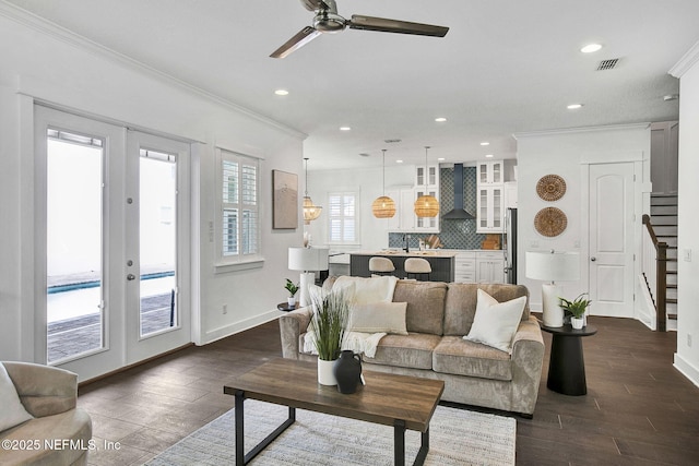 living area with ceiling fan, french doors, ornamental molding, and stairs