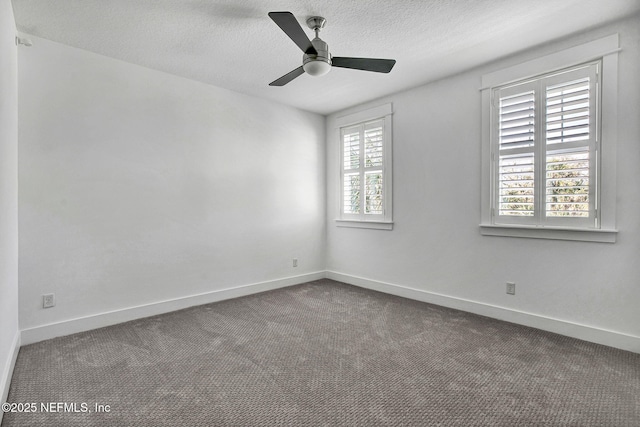 empty room with a ceiling fan, baseboards, dark carpet, and a textured ceiling