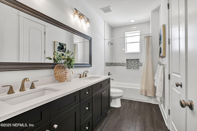 full bathroom featuring a textured ceiling, toilet, visible vents, and a sink