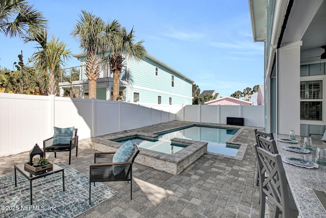 view of swimming pool with a patio, a fenced backyard, and a pool with connected hot tub