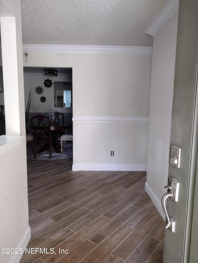 unfurnished room with wood finish floors, baseboards, a textured ceiling, and ornamental molding