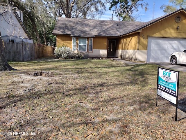 ranch-style home featuring a shingled roof, a front yard, a garage, and fence